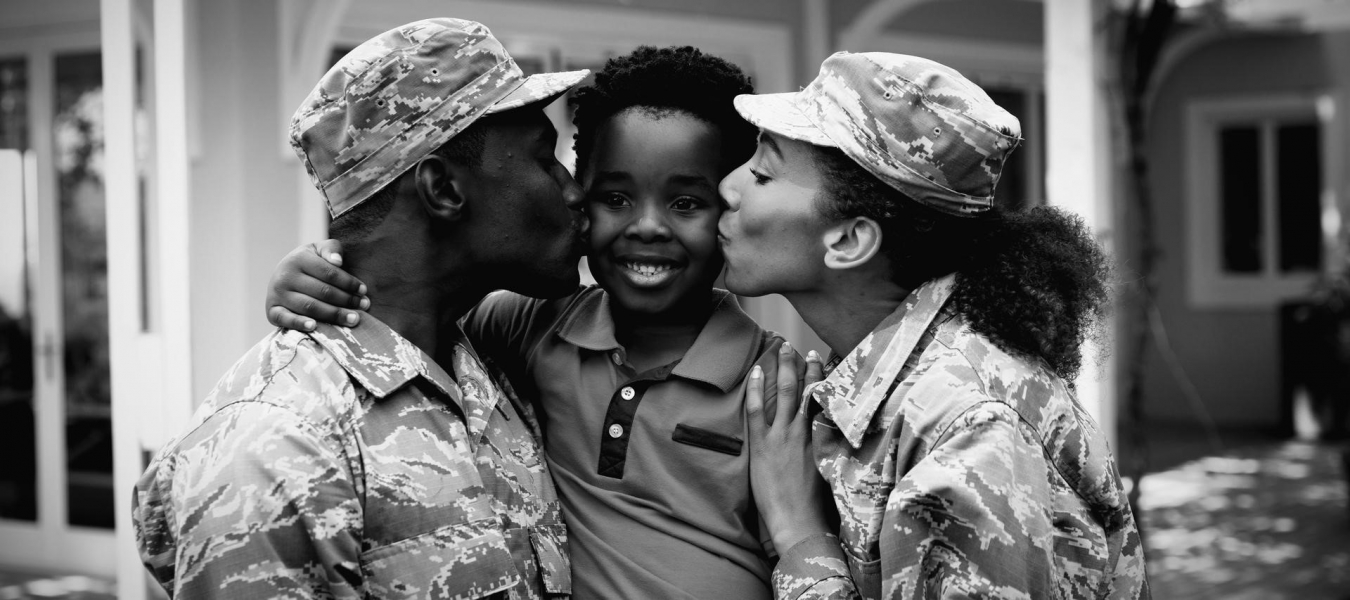 military parents kissing their sons cheek in front of their house